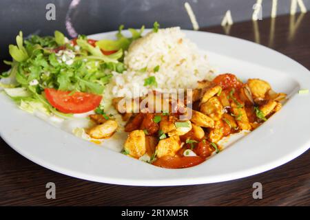 Braised chicken with vegetables and some rice and salad. Stock Photo