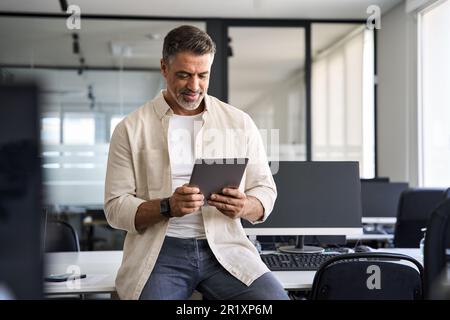 Senior businessman CEO holding digital tablet using fintech tab application. Stock Photo