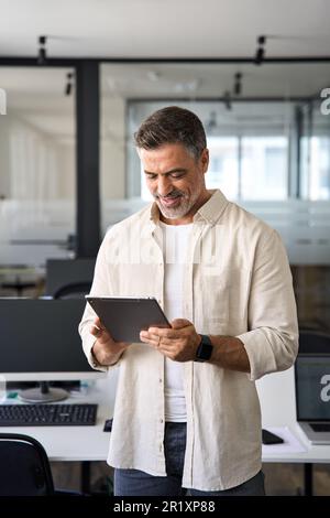 Vertical portrait Latin mature adult professional business man using tablet. Stock Photo