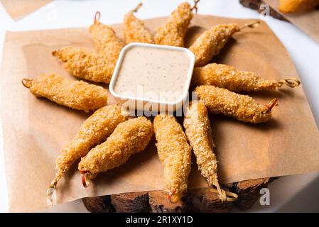 Deep Fried Shrimps with Dipping Sauce. Delicious golden-brown fried shrimps, breaded and deep-fried to perfection, served with a tangy dipping sauce. Stock Photo