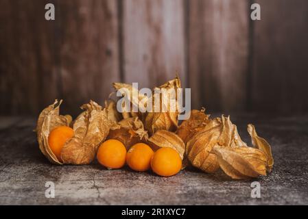 Still life of physalis on a brown wooden background. Stock Photo
