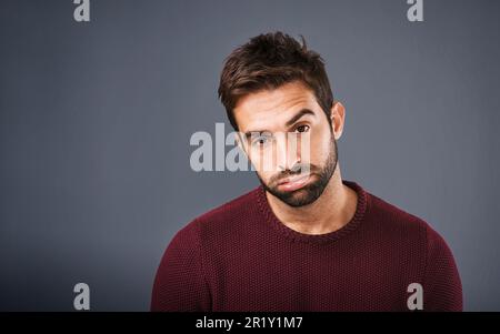 Bored, portrait and annoyed man in studio unhappy and moody against a grey background space. Sad face of depression and man with negative attitude Stock Photo