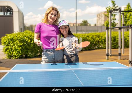 Young woman with her daughter playing ping pong in park Stock Photo