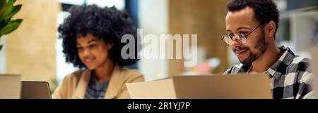Using modern technologies. Two young multiracial business people sitting at the desk, working together in coworking space Stock Photo