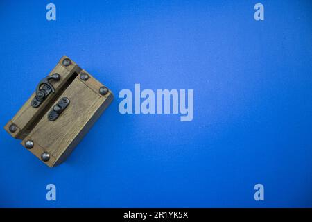 A wooden chest with a slightly open mouth, placed on the edge of the blue background. Stock Photo