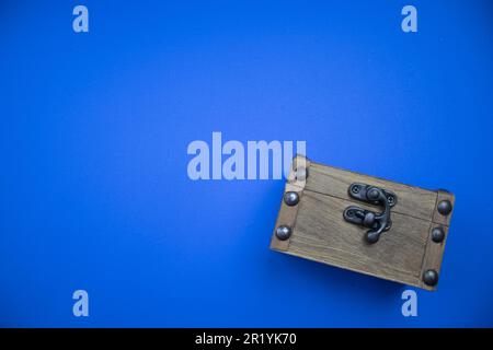 A locked wooden chest placed on the edge of the blue background. Stock Photo