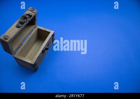 An open wooden chest, placed on the edge of the blue background. Stock Photo