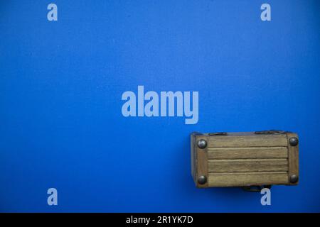 Wooden chest, placed on the edge of the blue background. Stock Photo