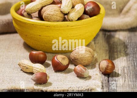 Mixed nuts in shell in a bowl, close-up. Nuts in the shell on a wooden background, space for text Stock Photo