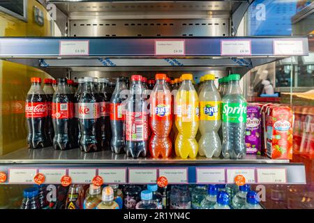 Carbonated soda drinks on sale on a shelf in a fridge in a shop Stock Photo