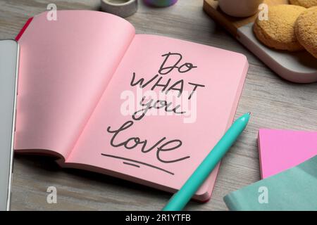 Open notebook with motivational phrase Do What You Love on wooden table Stock Photo