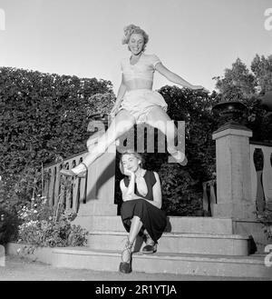 In the 1950s. An unknown young woman is pictured in the moment when jumping over her girlfriend who is sitting on the stairs. Sweden 22 july 1951. Conard ref 1744 Stock Photo