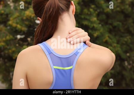 Young woman suffering from neck pain outdoors, back view Stock Photo