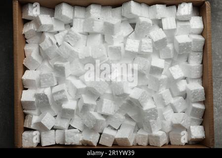 Cardboard box filled with polystyrene styrofoam pieces on grey background, top view Stock Photo