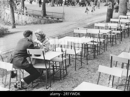 In the 1950s. A young couples sits on an outdoor cafe sharing a soda. They each have a straw and drinks from the same bottle or glass.  Sweden 1956 Stock Photo
