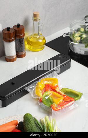 Sealer for vacuum packing with plastic bag of bell pepper on counter in kitchen Stock Photo