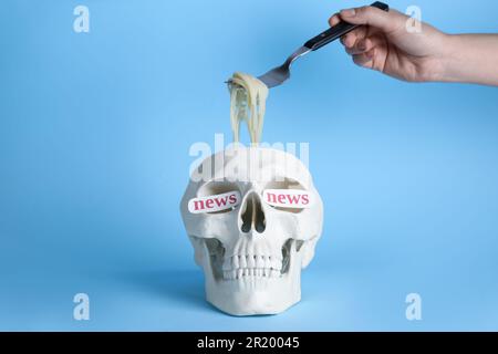 Information warfare concept. Woman taking noodles from human skull, closeup. Media news influence Stock Photo