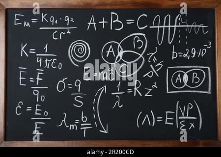 Different physical formulas written with chalk on blackboard Stock Photo