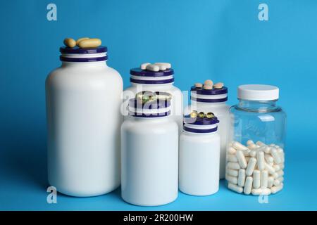 White medical bottles and different pills on light blue background Stock Photo