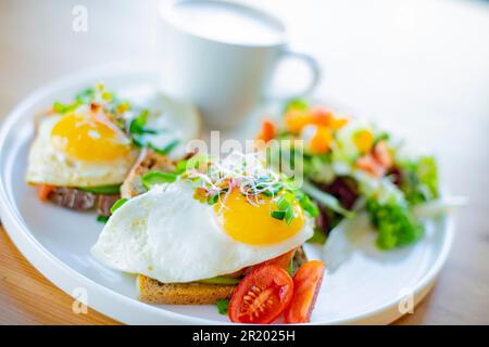 Breakfast with fried eggs on toasts on a restaurant table Stock Photo