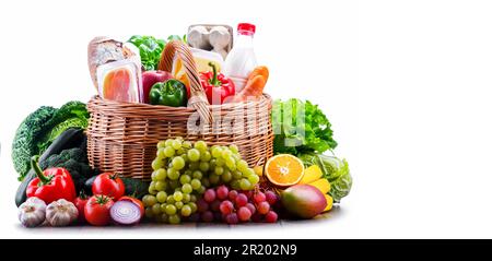 Wicker basket with assorted grocery products including fresh vegetables and fruits Stock Photo