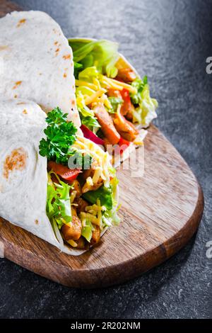 Tortilla with chicken and fresh vegetables on a cutting board Stock Photo