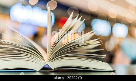 An open hardcover book on a table in a public library Stock Photo