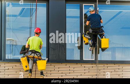 Two men cleaning windows on an office building Stock Photo