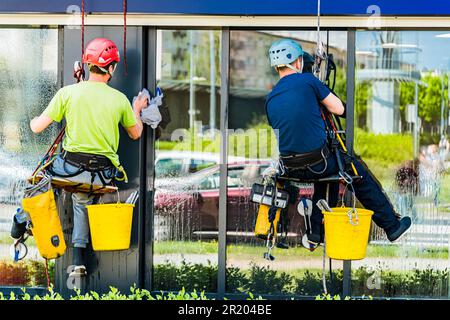 Two men cleaning windows on an office building Stock Photo