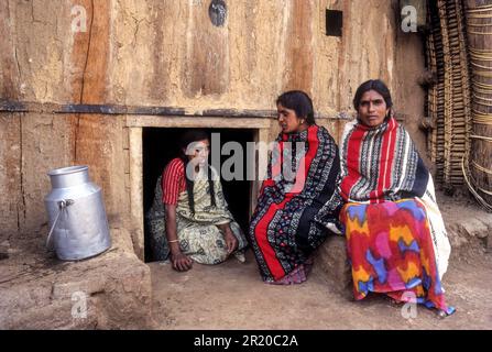 Toda tribe women in front of the hut, entry is through a carved wooden door so small that one has to crawl through it to enter at Kinnakorai Stock Photo