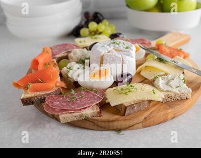 Platter with cold cut sandwiches on a wooden cutting board on kitchen table Stock Photo
