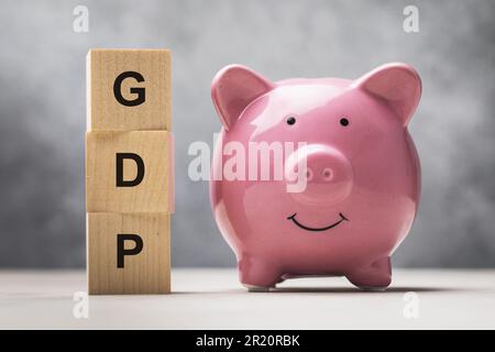 Piggy bank and wooden cubes with text on abstract background, concept on GDP theme Stock Photo