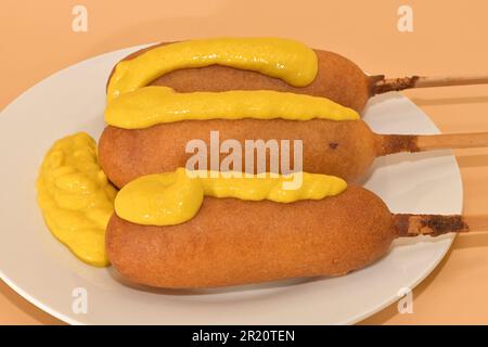 Freshly prepared corndogs on a plate with mustard. Stock Photo