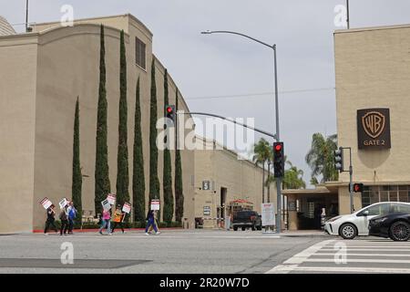 Burbank, California / USA - May 15, 2023: Writers Guild of America WGA members on strike carry picket signs while crossing the street in front of the Stock Photo