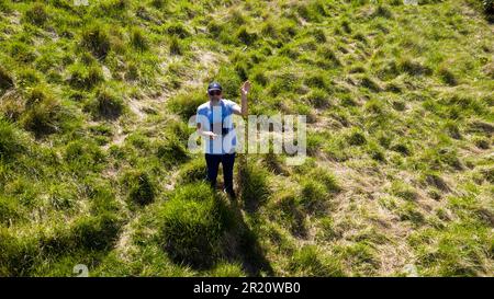 Drone Pilot, Smiling and waving at the Drone, flying just above his head, on Coxhill Mount, Kearsney, Kent Stock Photo