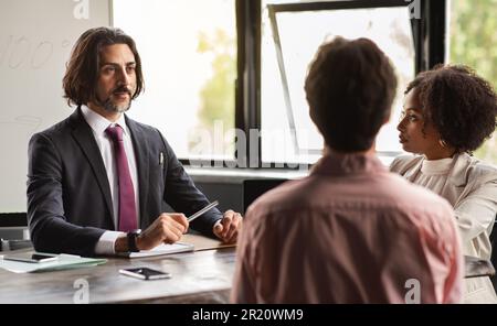 Mature businessman leader mentor talking to diverse colleagues team Stock Photo