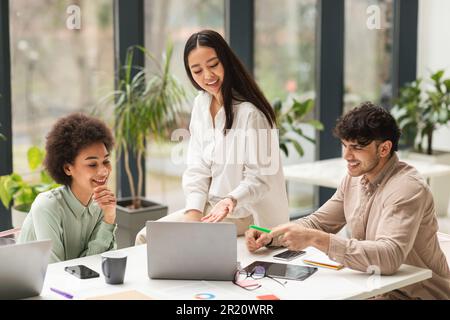 Group Of Diverse Coworkers Using Laptop Discussing Project In Office Stock Photo