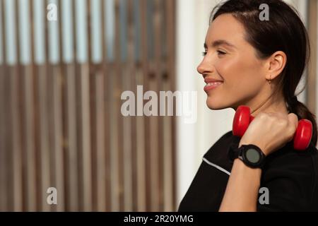 Happy millennial european woman athlete in sportswear doing arm exercises with dumbbells in city, close up Stock Photo