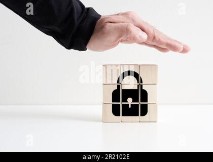 Security and protection concept. Data or identity privacy or safety. Protective hand on the wooden cubes with padlock icon. Stock Photo