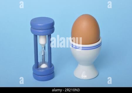 Boiled egg and hourglass on a blue background Stock Photo