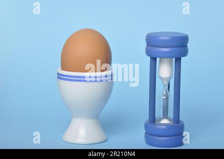 Boiled egg and hourglass on a blue background Stock Photo