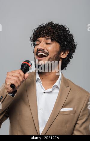 Cheerful and young indian host of event with curly hair standing in 