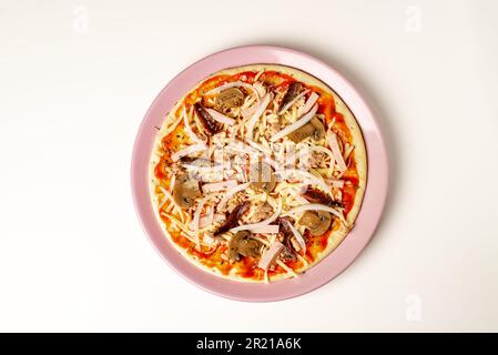 Plate with a pizza ready to bake, with vegetables, tuna, cooked ham and anchovies. Stock Photo