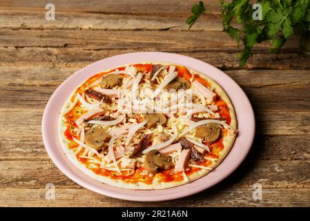 Plate with a pizza ready to bake, with vegetables, tuna, cooked ham and anchovies. Stock Photo