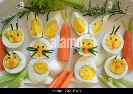 Easter appetizer of boiled eggs in the form with bunny face and carrots on plate, top view ,Italy Stock Photo