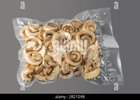 Cultivated white champignon mushrooms, sliced button mushrooms (Agaricus bisporus) in vacuum-packed for sous vide cooking on gray background Stock Photo