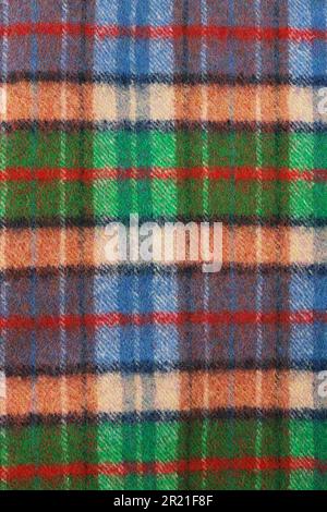 Wool plaid texture. Soft and warm folded alpaca wool blanket. Green and orange wool plaid texture macro shot. Wool coat Stock Photo