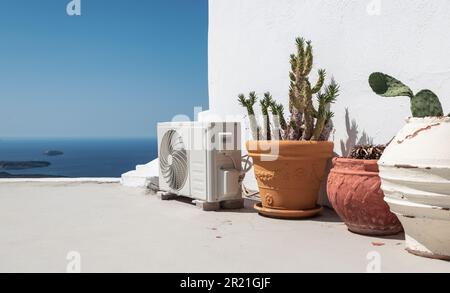 Air conditioning or heat pump unit near potted plants in Santorini, Greece. Stock Photo