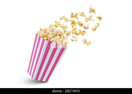Popcorn flying out of pink white striped paper box isolated on white background with copy space. Splash, levitation of popcorn grains. Stock Photo