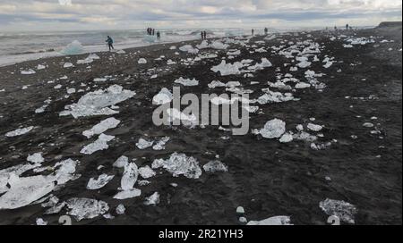 A group of people walking along a Diamond beach located by Jokulsarlon glacier lagoon Stock Photo